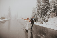 Bride and groom running down a snow-covered mountain road during a winter elopement, captured by a PNW elopement photographer.