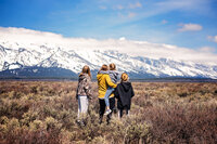 Caryn Dodson and her three daughters standing together facing the Grand Tetons, outdoor family photographer based in Michigan