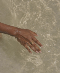 Image showcasing a hand gently placed in clear water, representing the serene and natural elements of Brave Beauty Spa, a Virginia Beach esthetician salon.