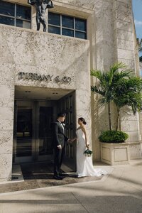 bride and groom hold hands outside of tiffany & co in south florida