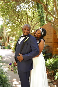 Black couple embracing on their wedding day at their garden venue