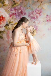 Mother and daughter in gowns looking at each other smiling during photoshoot in La Vernia