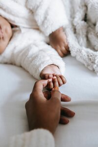 baby sleeping holding adult hand