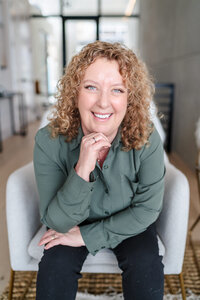Renee Warren wearing black top and pink skirt leaning on railing and smiling at camera