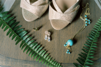 Fine art detail picture of brides high heels, ear rings, and necklace with green fern leaves acent