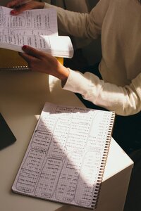 Kaya flipping through a handwritten notebook, with a full page of notes visible on the desk.