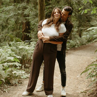 A photo of Ahna Maria Photography and her husband in the redwood forest in California.