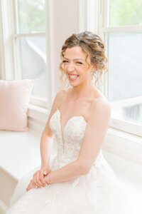 The bride smiles at the camera in her wedding dress.