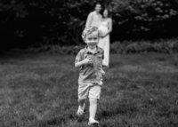 Two people are in the background who are tickling the little girl who is the focus of the picture who is laughing and her hair is flowing from the movement.