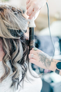 Close up brand image of a hair stylist working on curling a bride's hair for her wedding