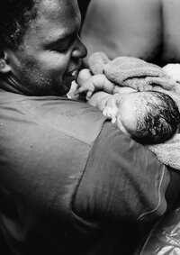 Black father holding baby after birth