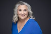 woman with long gray hair smiling and wearing a blue shirt