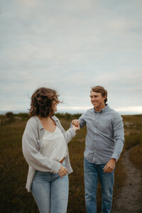 Engagement couple walking by grass on Wilmington Beach