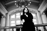 Black and white headshot brunette author in train station in black dress
