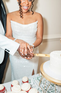 A newlywed couple cutting a wedding cake together