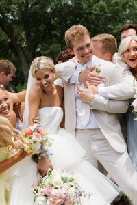Bride and groom are hugged by their wedding party