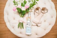 flower bouquet, painted wine bottle and shoes on  a tufted ottoman