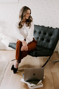 Copywriter for websites Erika Fitzgerald sitting in a chair looking at a laptop, reviewing website copy strategy notes