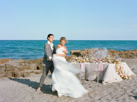A Couple spins bluirrily on the beach on their wedding day.