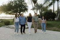 family of five holds hands and smiles for a family photo session in south florida