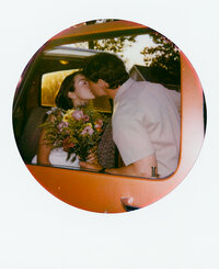Polaroid photo of an engaged couple sharing pizza on the floor of a styled indoor set with tropical leaves and disco balls — captured by a film wedding photographer during an engagement session.