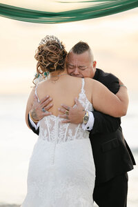 Groom cries as he holds his bride in his arms after she just walked down the aisle. This was an emotional beach wedding in Sarasota, captured by wedding photographer in Sarasota FL