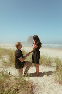 A man proposes to his girlfriend on the beach. She's surprised, but so happy.