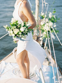 Elegant film photo of a bride on a sailboat during her Palm Beach wedding, surrounded by sunset light and soft coastal tones.