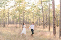 Groom leading bride through forest smiling