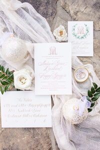 flat lay of wedding invitations next to white flowers and vases