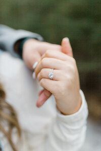 Man and womans hands holding each other featuring a beautiful engagement ring