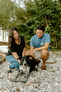 couple kneeling down to pet black and white rescue dog