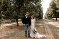 bride and groom holding hands photo taken in a pecan orchard