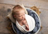 Newborn baby boy in gray bowl