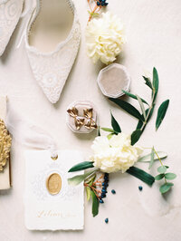 a flatlay with white wedding shoes, gold earings, and white flowers in Tuscany, Italy