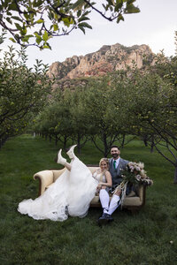 bride and groom sitting on a couch in an orchard
