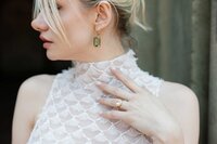 Bride looks over her shoulder and shows off engagement ring in central park.