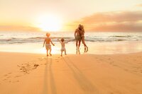 boy running toward mom and dad on the beach in hawaii during sunset photoshoot