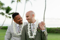 A person with their arm around their partner as they smile on their wedding day 