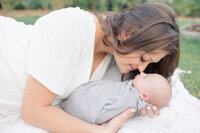 A close-up of a mother and her newborn, with the mother gently touching noses with her infant, both sharing a tender, joyful moment. The mother's smile radiates love and warmth as she cherishes the intimate connection with her baby