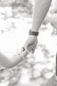 A close up image of a dad holding his daughter's hand during their sunset photo session in Grand Forks, ND. 