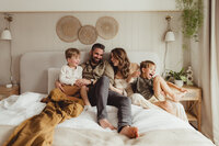 A family photograph of Carley Aplin sitting on the bed laughing with her family s
