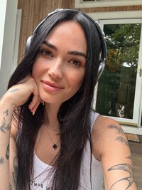 woman softly smiling at camera with headphones on