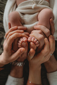 a photo of a baby feet with his parents hansds wrapped around them