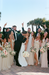 Beach wedding photo of the wedding party featuring romantic kiss from bride and groom in South Florida | SushDigitalMedia