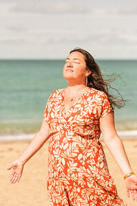 Natacha, tête levée vers le ciel, yeux fermée dans un décor de plage.