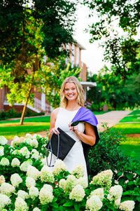 Senior standing in white flower bush on Trevecca campus