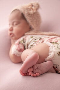 detail photo of a newborn baby girl's feet with the body faded in the background.