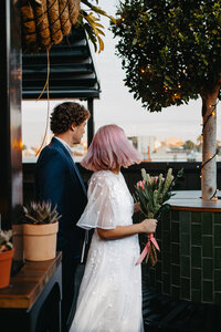 modern bride and groom at rooftop bar with bouquet