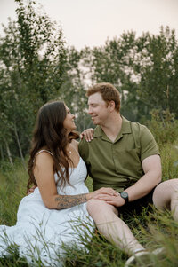 engaged couple sitting in a field together